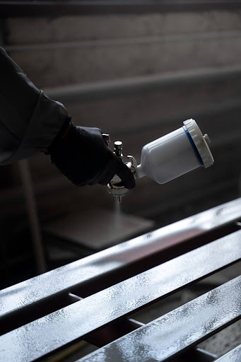 Imagem de peças metálicas fosfatizadas preparadas para pintura industrial em ambiente fabril.
