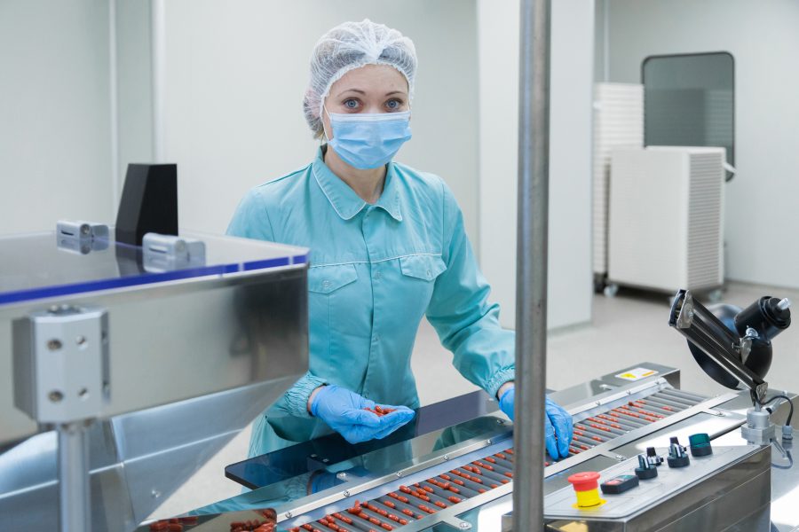 Pharmaceutical technician in sterile environment working on production of pills at pharmacy factory